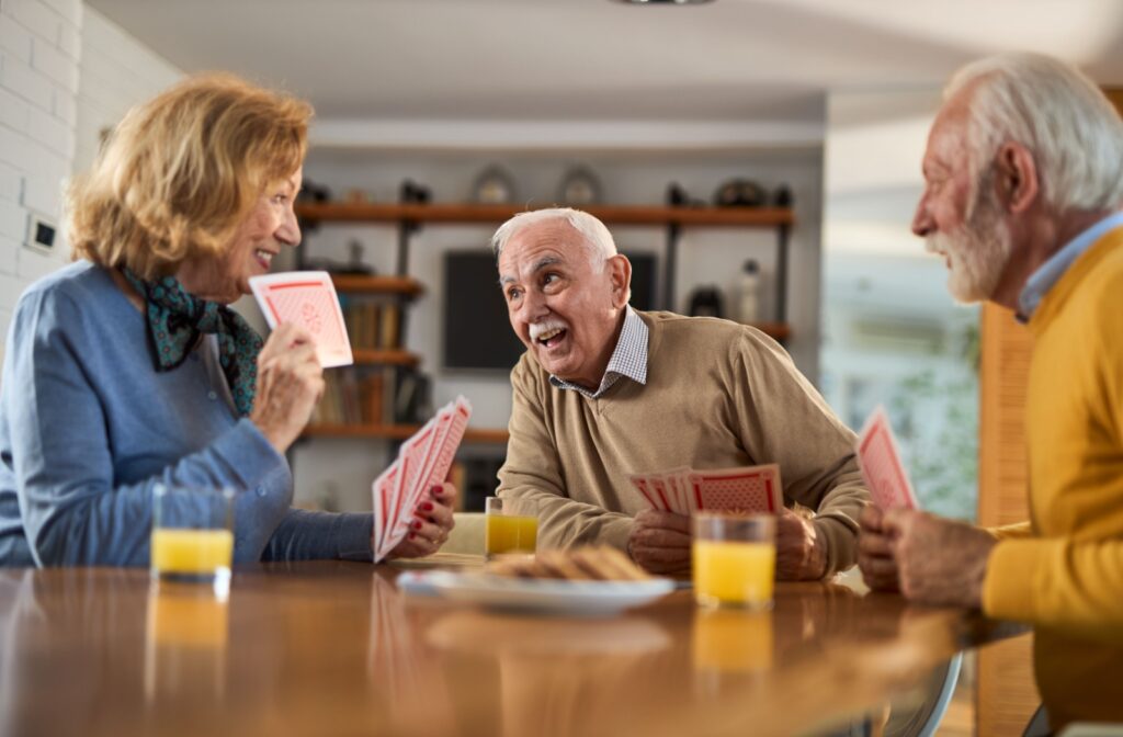 A group of older adults playing cards and laughing at a table.