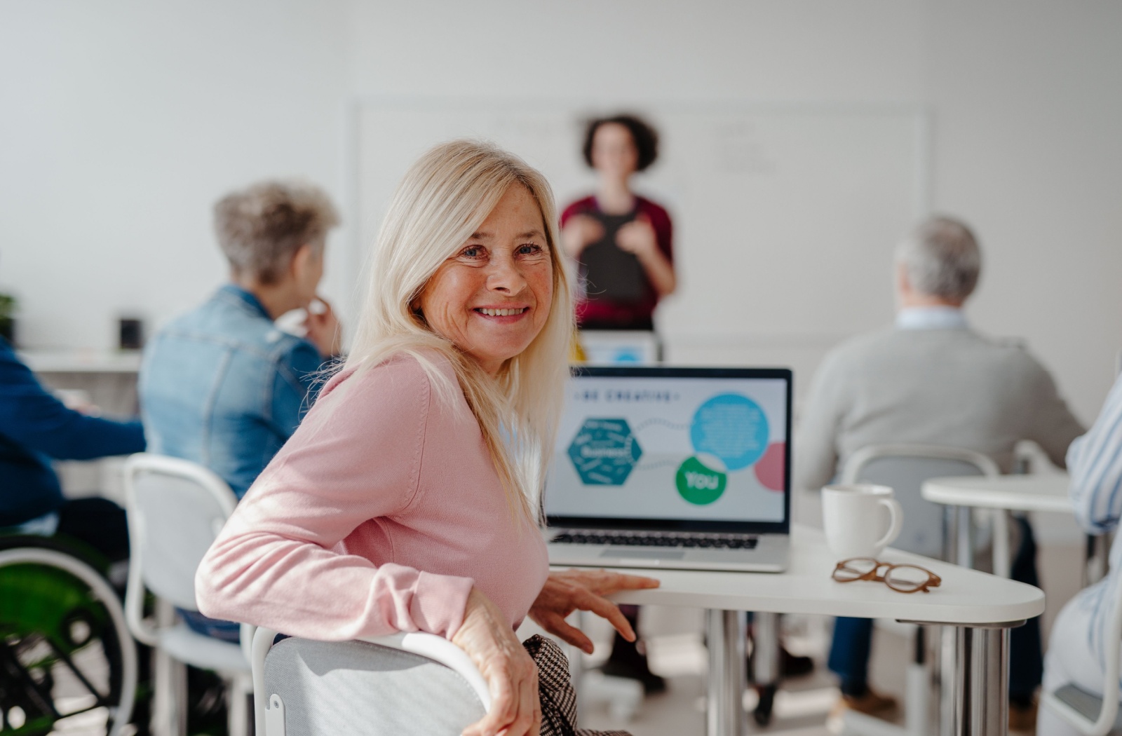 A senior smiles while taking a class to improve their digital literacy to keep themselves safe from cyber attacks and scams.